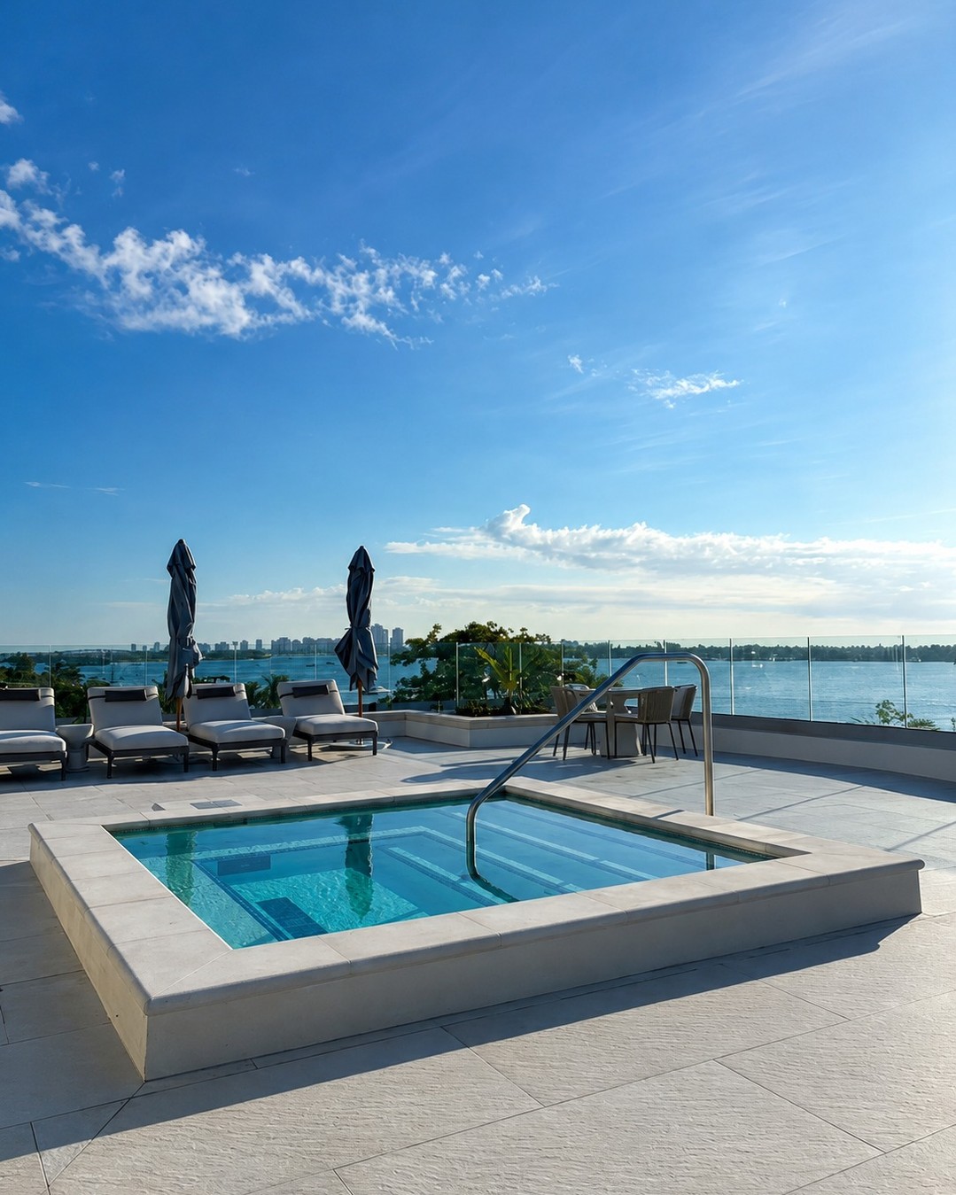 Square modern spa on a white stone terrace overlooking the bay with lounge chairs